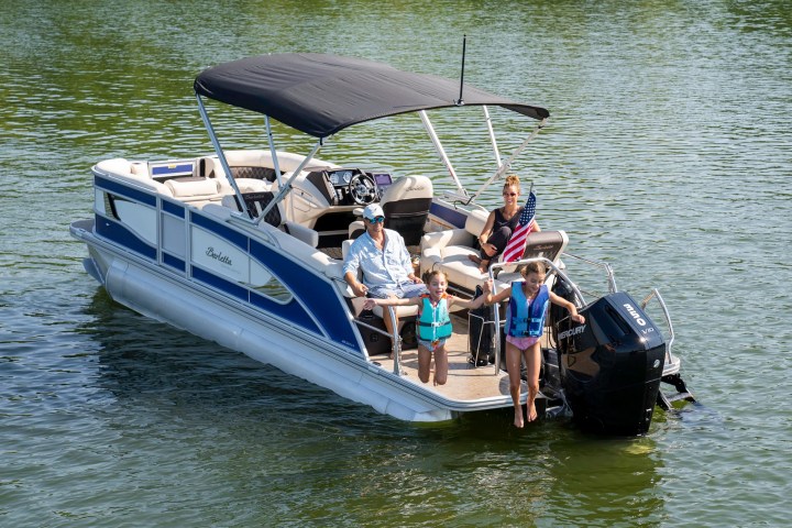 Family on motorboat with two children in life jackets at rear; American flag visible.