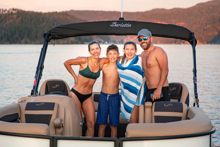 A smiling family on a boat at sunset with mountains in the background.
