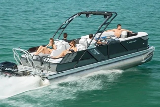 Five people relaxing on a moving pontoon boat in a large body of water.
