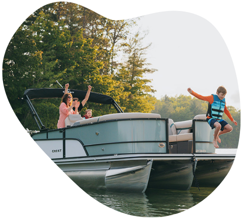 Child jumping off boat into lake, people on board waving, trees in background.